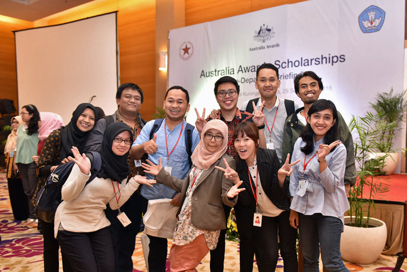 A group of students posing in front of Australia Awards Scholarships banner